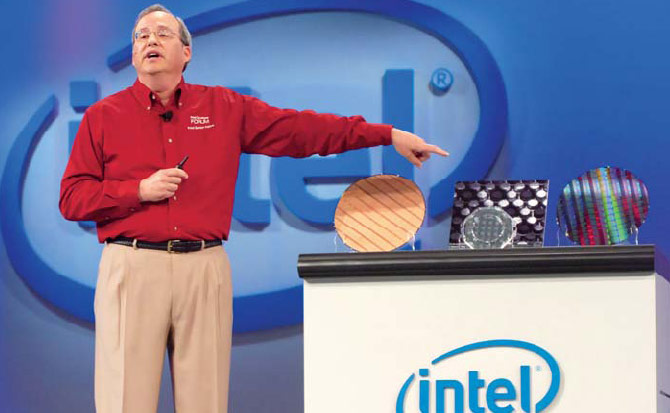 Джастин Раттнер указывает на основные достижения инженеров Intel — кремниевую пластину с 80-ядерными процессорами, технологию пакетирования памяти в одном корпусе с процессором и пластину с чипами, содержащими гибридные лазеры